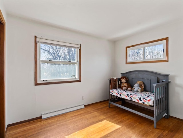 bedroom with baseboards, light wood-style floors, and a baseboard radiator