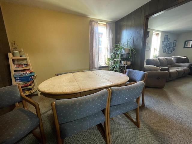 dining room featuring wooden walls and carpet floors