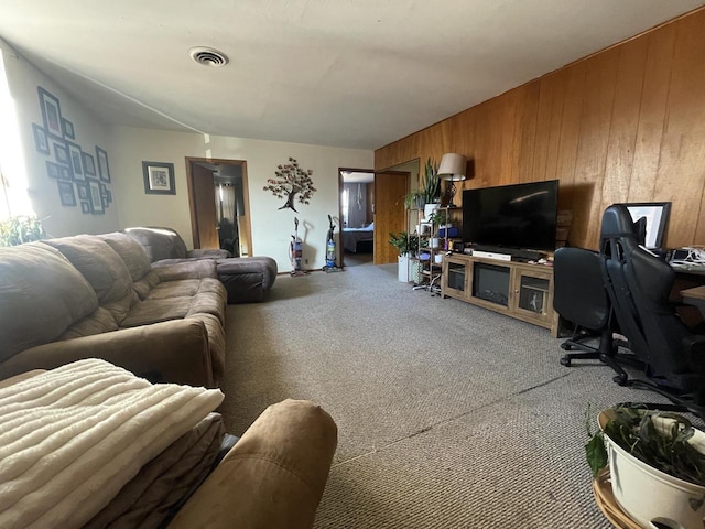 living room featuring wooden walls, carpet, and visible vents