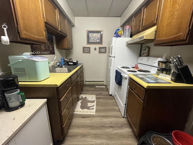 kitchen with under cabinet range hood, light countertops, baseboard heating, white electric stove, and a sink