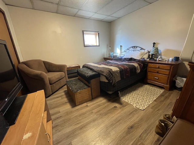 bedroom with light wood-style floors and a drop ceiling