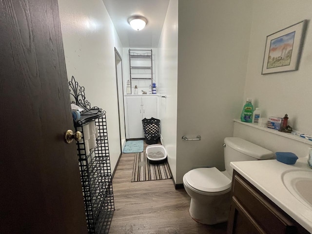 bathroom with toilet, vanity, baseboards, and wood finished floors