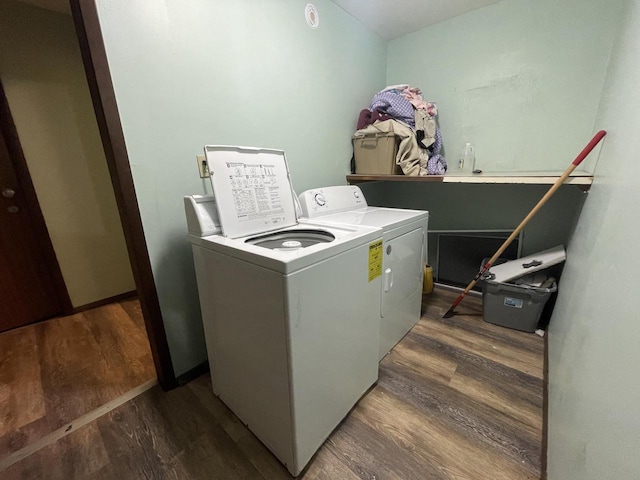 clothes washing area featuring separate washer and dryer, wood finished floors, and laundry area