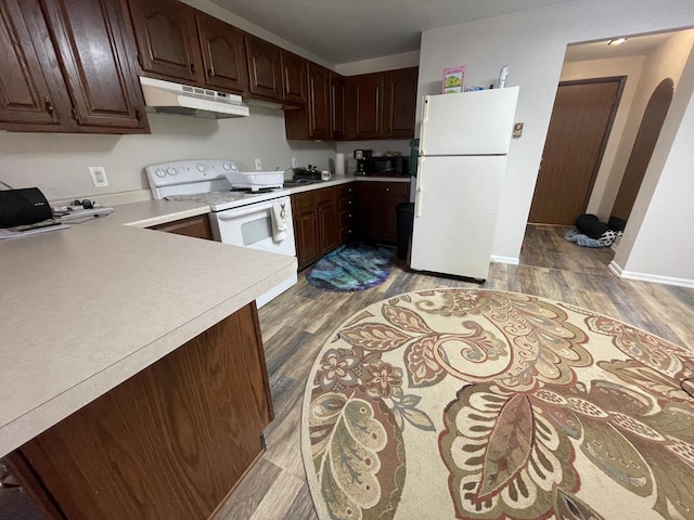 kitchen featuring white appliances, arched walkways, light countertops, light wood-style floors, and under cabinet range hood