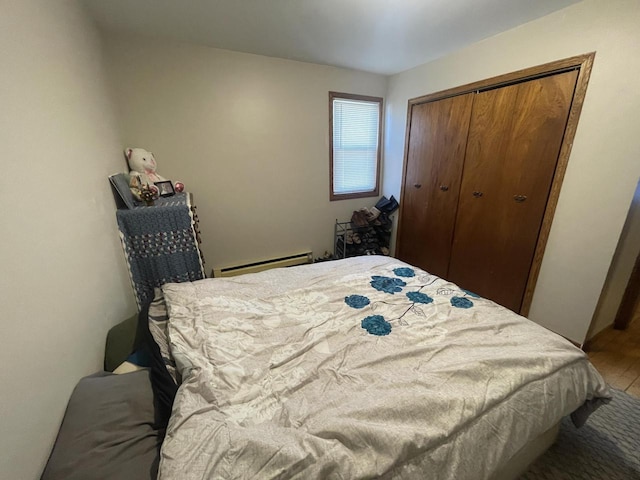 bedroom featuring a baseboard heating unit and a closet