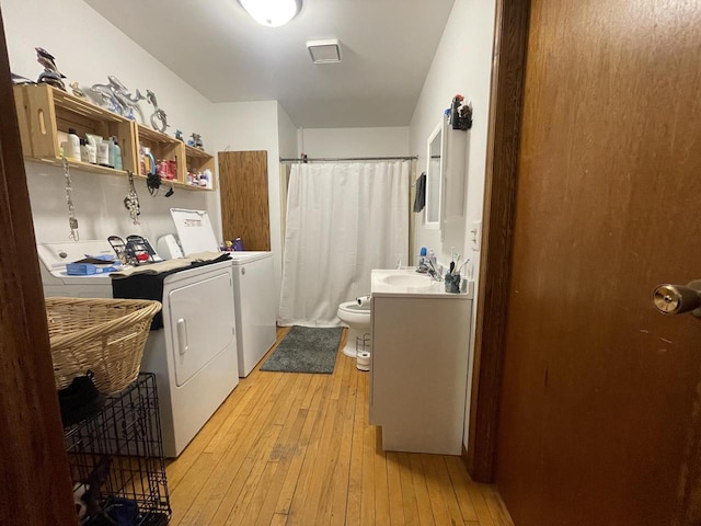 laundry room featuring laundry area, light wood-style flooring, independent washer and dryer, and a sink