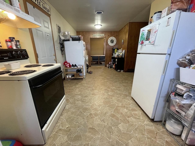 kitchen with under cabinet range hood, visible vents, freestanding refrigerator, and range with electric stovetop