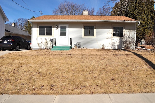 ranch-style house featuring a front lawn and a chimney