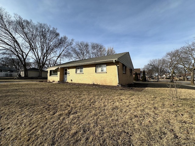 view of side of home with brick siding and a lawn