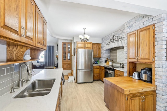 kitchen featuring backsplash, butcher block countertops, light wood-style flooring, appliances with stainless steel finishes, and a sink