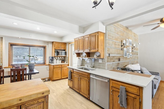 kitchen with beam ceiling, appliances with stainless steel finishes, light wood-style floors, and a sink