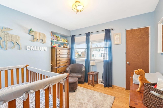 bedroom featuring a crib and light wood finished floors