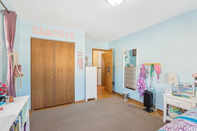 carpeted bedroom featuring a closet and baseboards