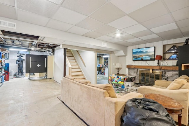 living area with a drop ceiling, a fireplace, stairs, and visible vents