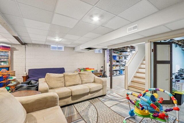 living area featuring visible vents, stairway, and a drop ceiling