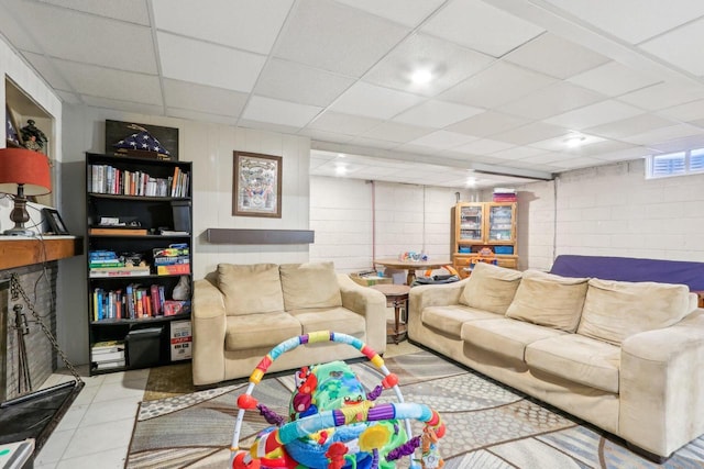 tiled living area featuring a paneled ceiling and concrete block wall