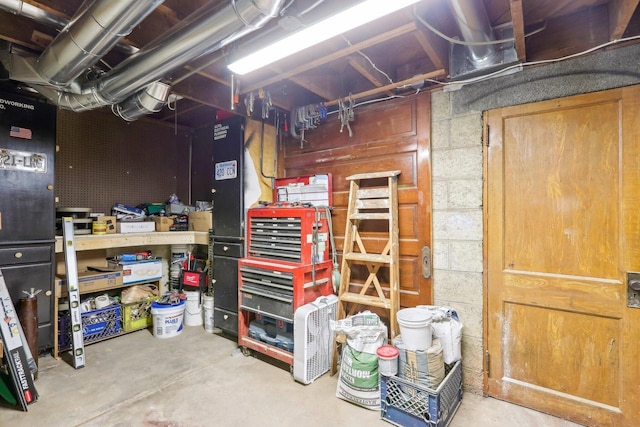 unfinished basement featuring a workshop area and concrete block wall