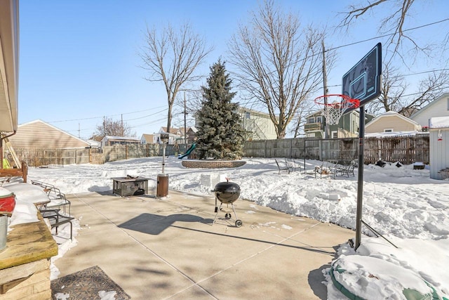 snow covered patio featuring area for grilling and a fenced backyard