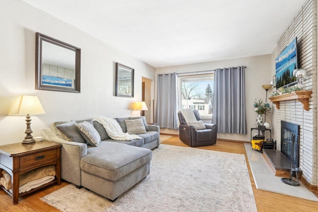 living area with a brick fireplace and wood finished floors