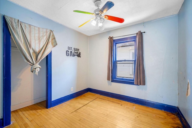 empty room with baseboards, wood-type flooring, a textured ceiling, and ceiling fan