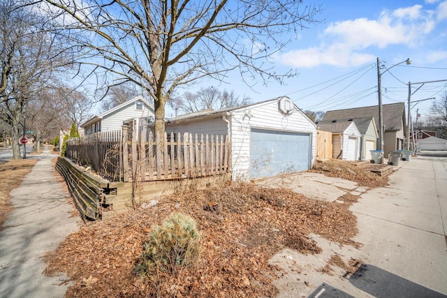 exterior space featuring a detached garage, fence, and an outbuilding