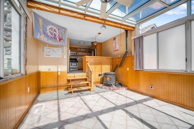 unfurnished sunroom with a skylight and a wood stove