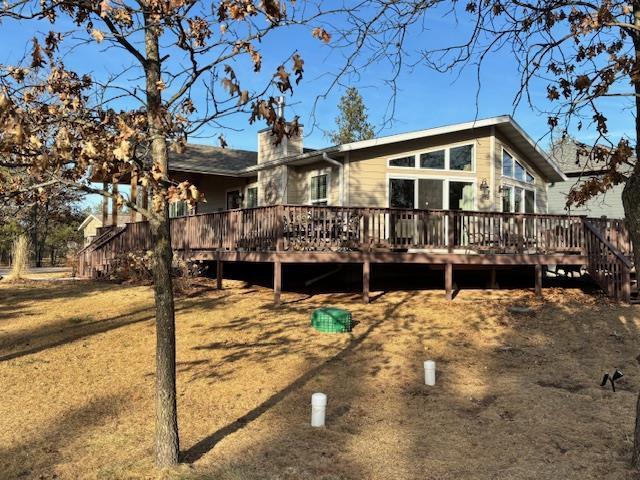 back of property with stairs, a wooden deck, and a chimney