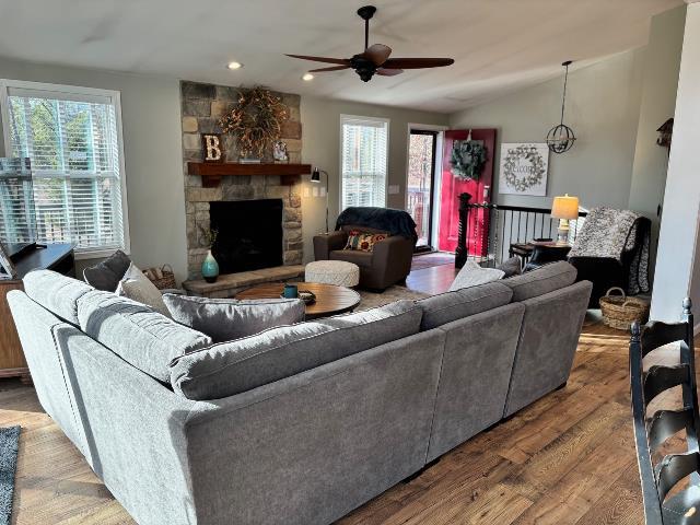 living area with wood finished floors, lofted ceiling, a fireplace, recessed lighting, and ceiling fan