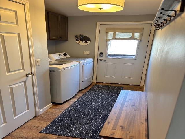 laundry room featuring light wood-type flooring, cabinet space, and washing machine and dryer