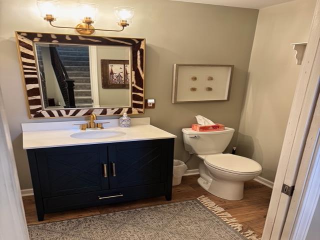 bathroom with vanity, toilet, wood finished floors, and baseboards