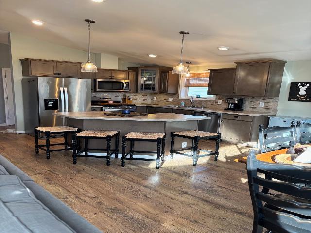 kitchen with backsplash, a center island, dark wood-type flooring, lofted ceiling, and appliances with stainless steel finishes