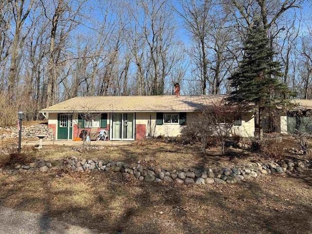 single story home with a chimney and metal roof