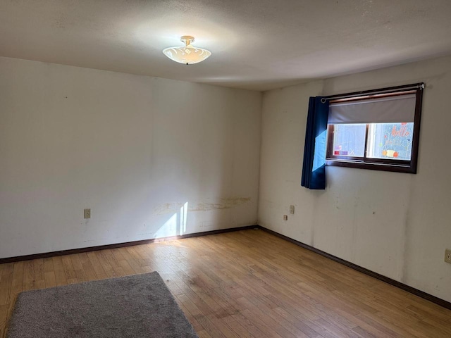 empty room featuring baseboards and wood-type flooring