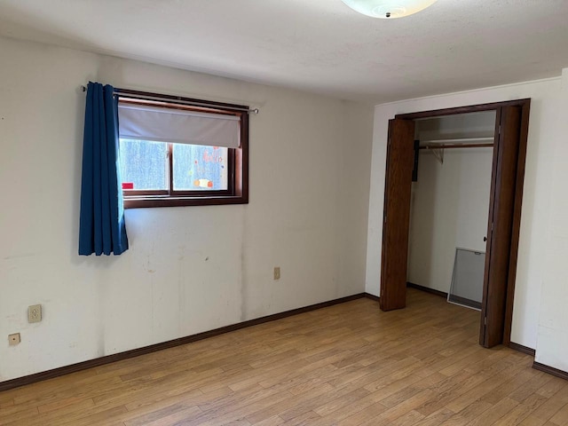 unfurnished bedroom featuring light wood finished floors, a closet, and baseboards