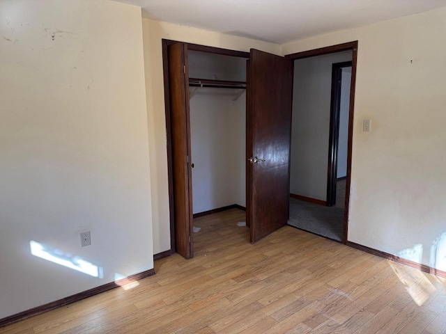 unfurnished bedroom featuring a closet, light wood-style flooring, and baseboards