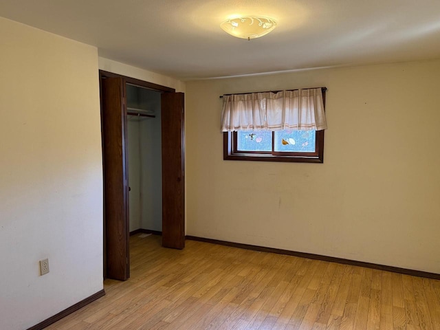 unfurnished bedroom with a closet, baseboards, and light wood-style flooring