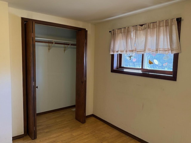 unfurnished bedroom with light wood-style floors, a closet, and baseboards