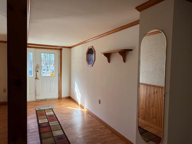 foyer entrance featuring light wood finished floors, baseboards, and ornamental molding