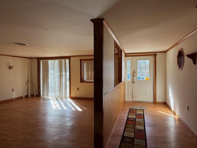 foyer entrance featuring visible vents, wood finished floors, baseboards, and ornamental molding