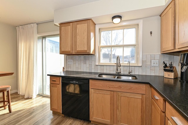 kitchen featuring tasteful backsplash, light wood-style flooring, black dishwasher, and a sink