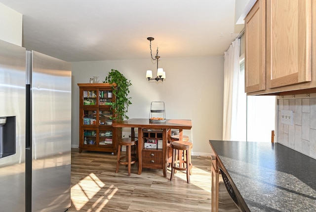 dining area with light wood-type flooring, baseboards, and a notable chandelier