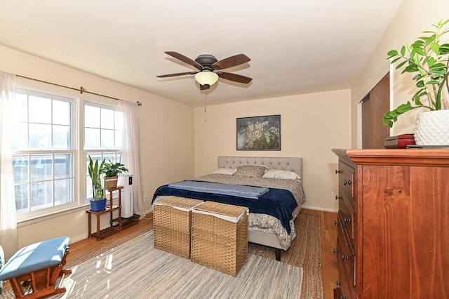 bedroom featuring light wood-style flooring, a ceiling fan, and baseboards