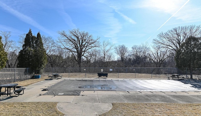 community pool with a patio area and fence