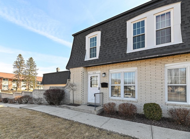 view of front of house with brick siding and a shingled roof