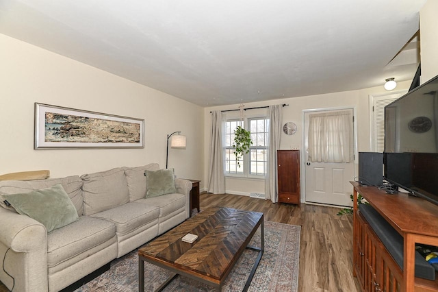 living area with visible vents, baseboards, and wood finished floors