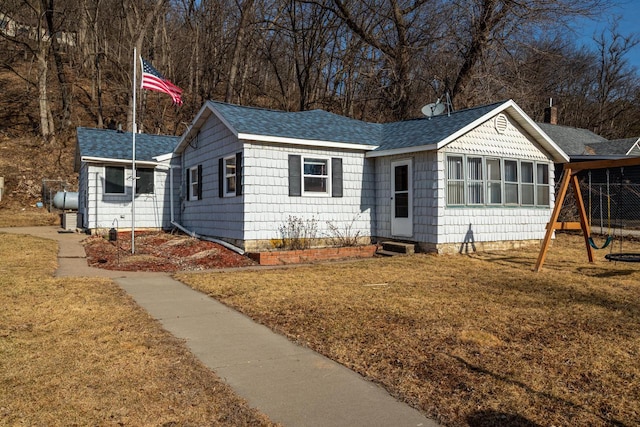 ranch-style house featuring entry steps, a front yard, a playground, and a shingled roof