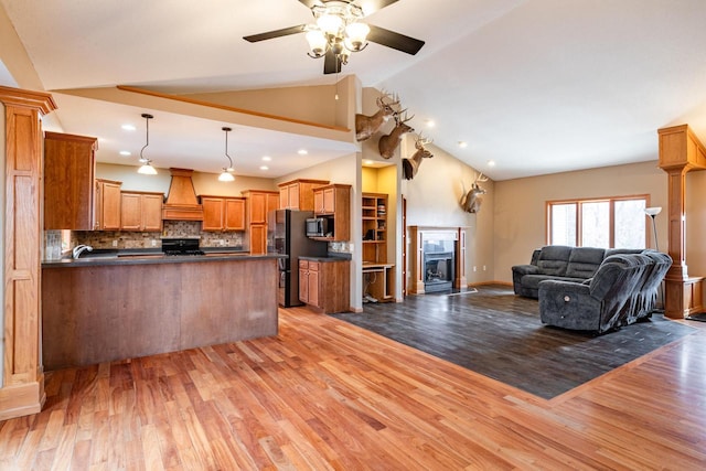 kitchen with a peninsula, custom exhaust hood, freestanding refrigerator, dark countertops, and open floor plan