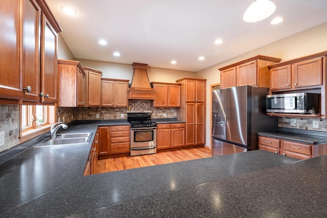 kitchen featuring premium range hood, brown cabinets, a sink, backsplash, and stainless steel appliances