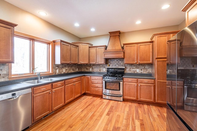 kitchen featuring a sink, stainless steel appliances, dark countertops, and premium range hood