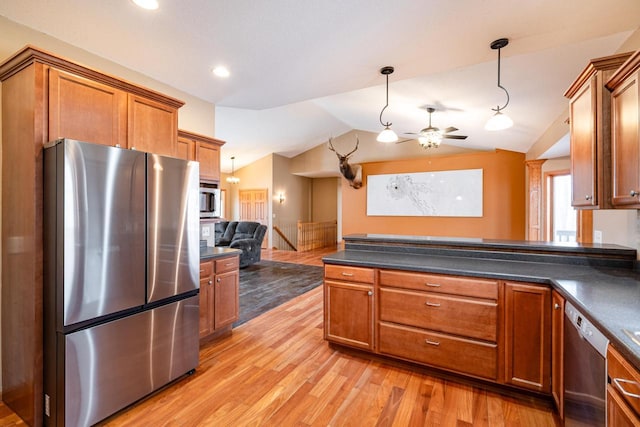 kitchen featuring dark countertops, open floor plan, brown cabinets, and appliances with stainless steel finishes